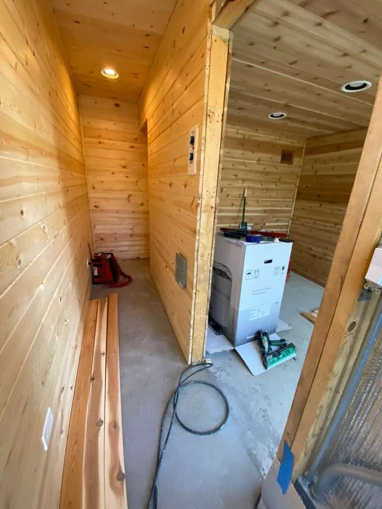 Cedar-paneled interior rooms with recessed lights during construction