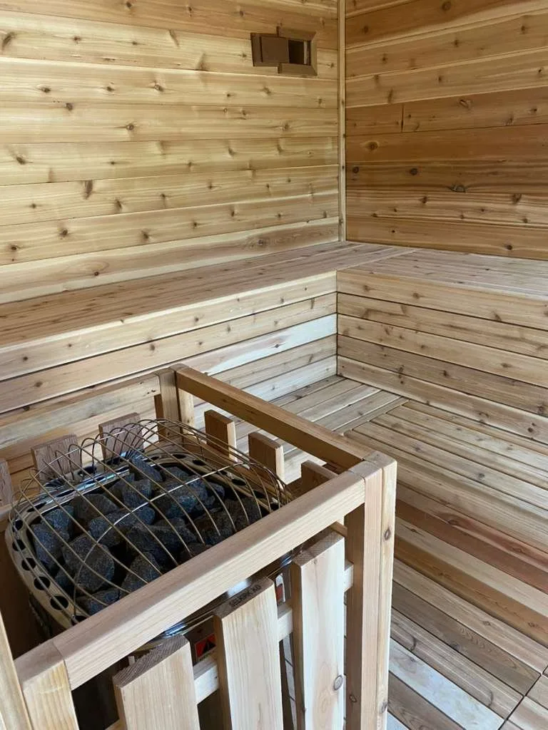 Cedar-lined room with a wall bench and a heater behind a wood guard
