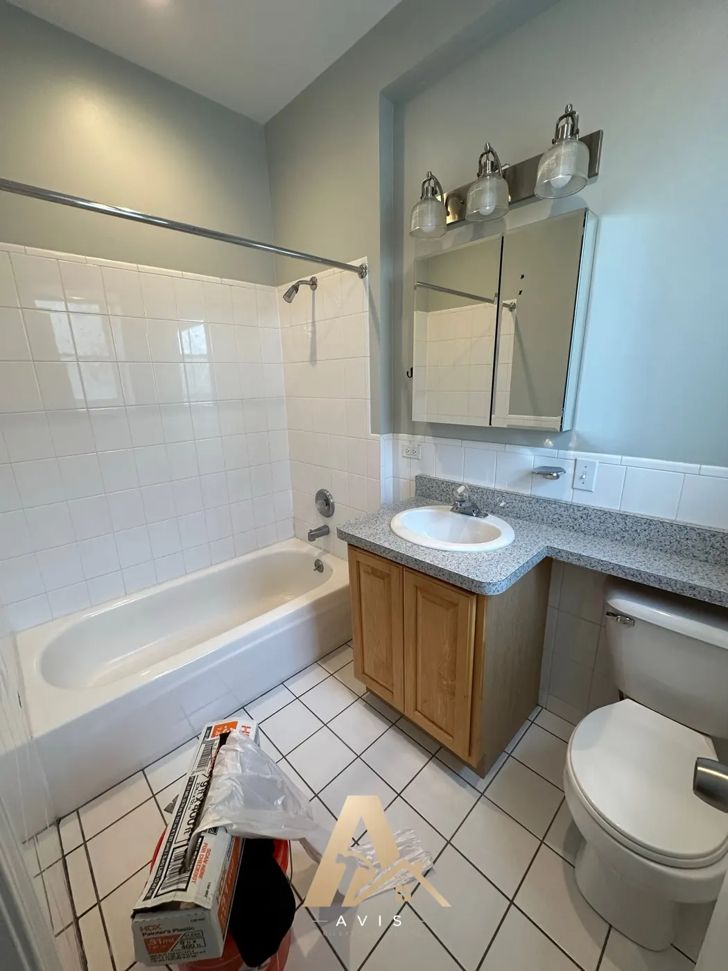 The bathroom before the remodel, with an oak vanity and white tile