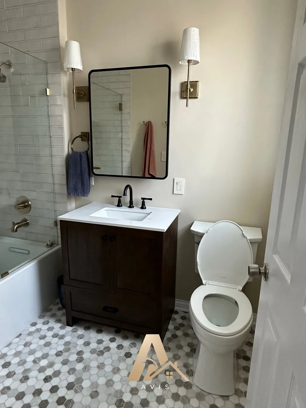 Brown vanity with a black-framed mirror and wall sconces