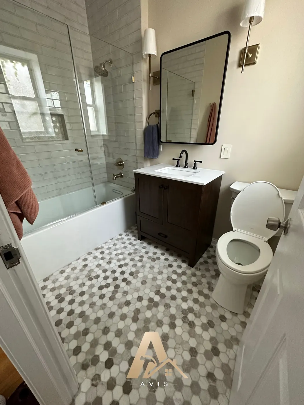 The vanity wall with a mirror, sconces, and towel ring