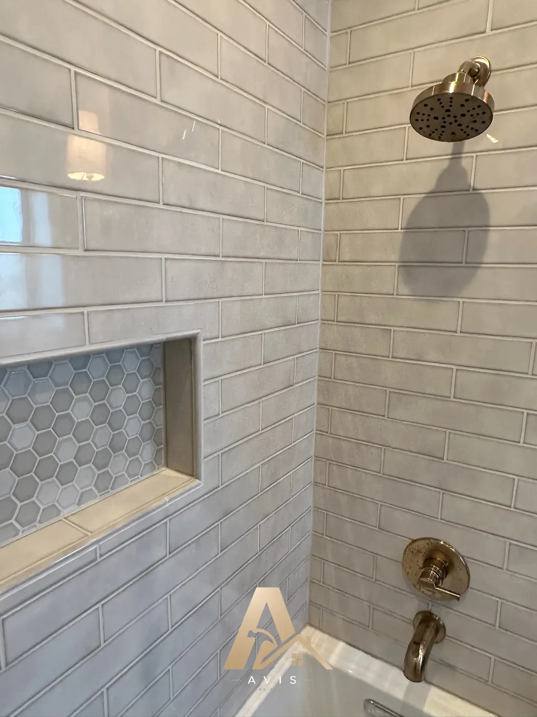 New shower head and fixtures above the tub with subway-style tile
