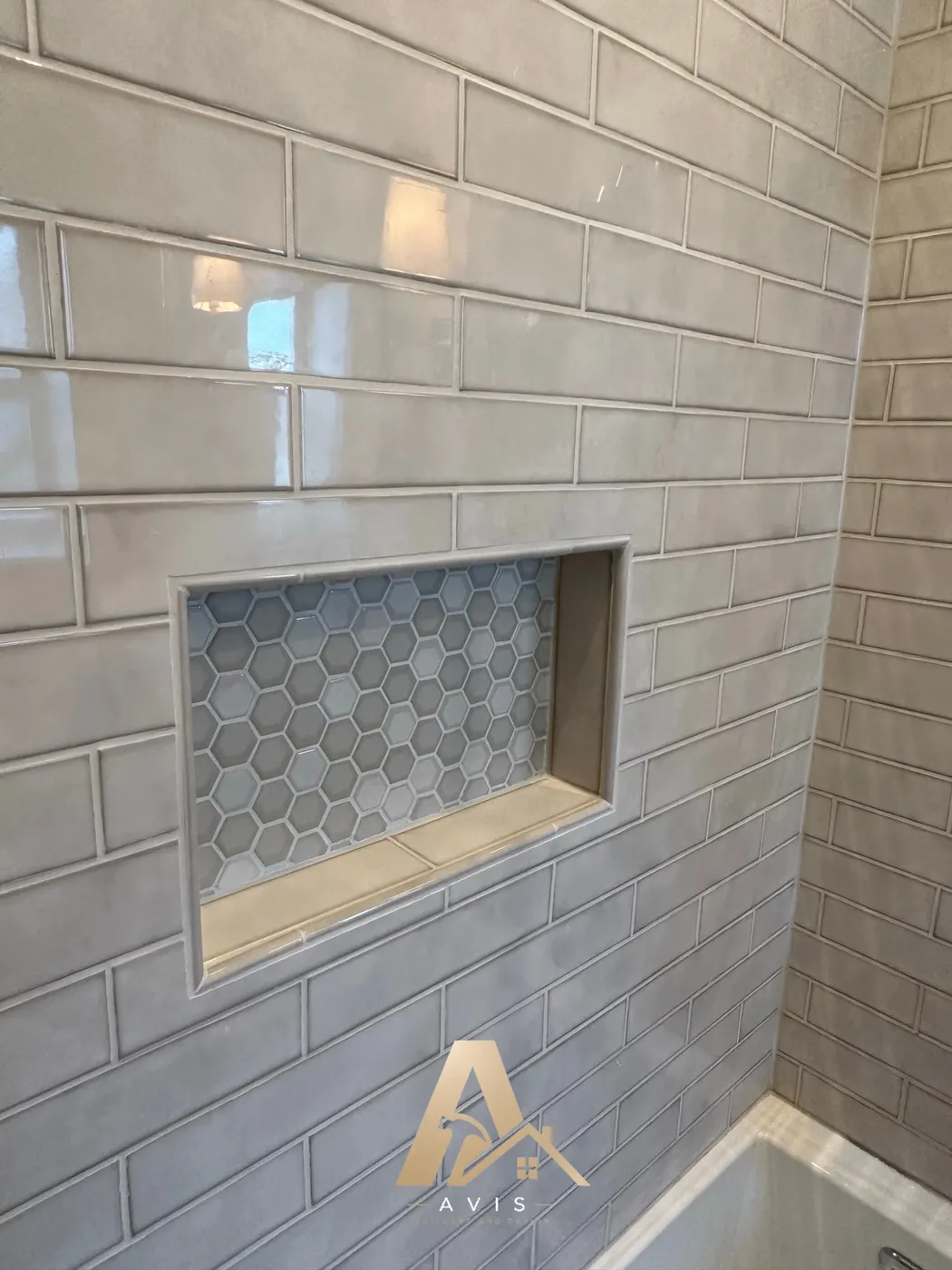 Built-in shower niche finished in mosaic tile within glossy subway wall tile