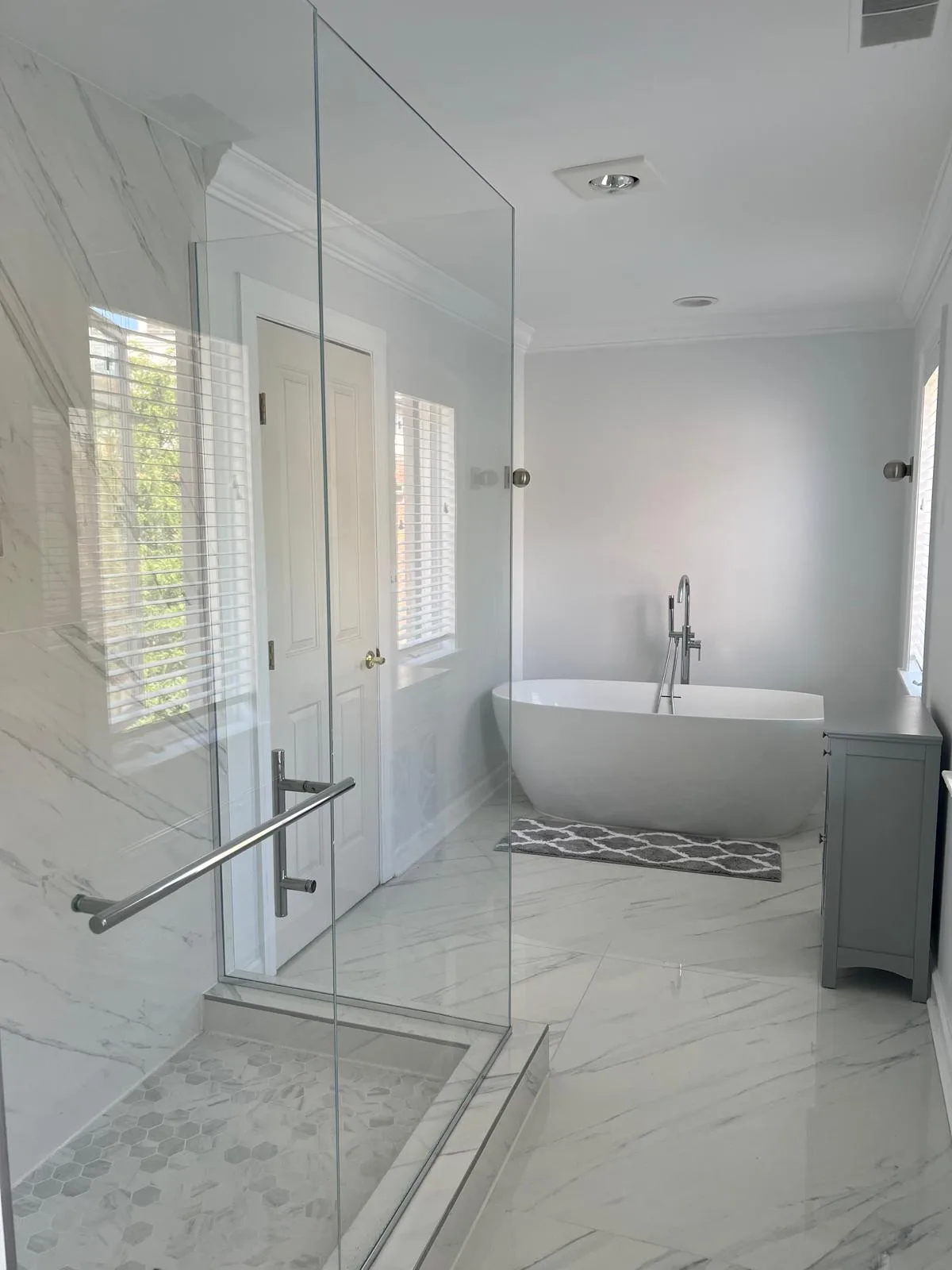 Marble-tiled bathroom with a freestanding tub and frameless glass shower