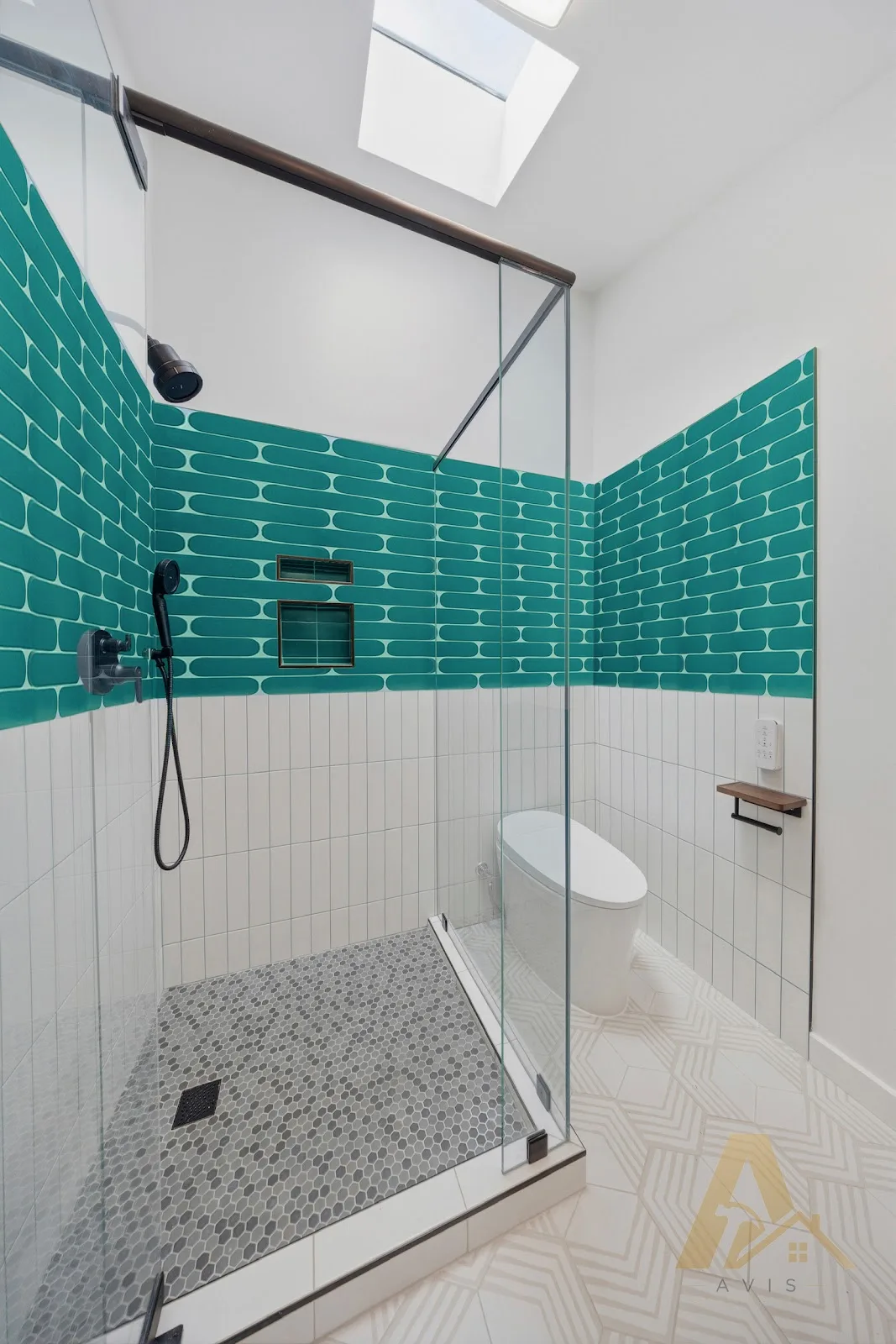 Teal tile shower with a glass enclosure, lit by a skylight in the ceiling above