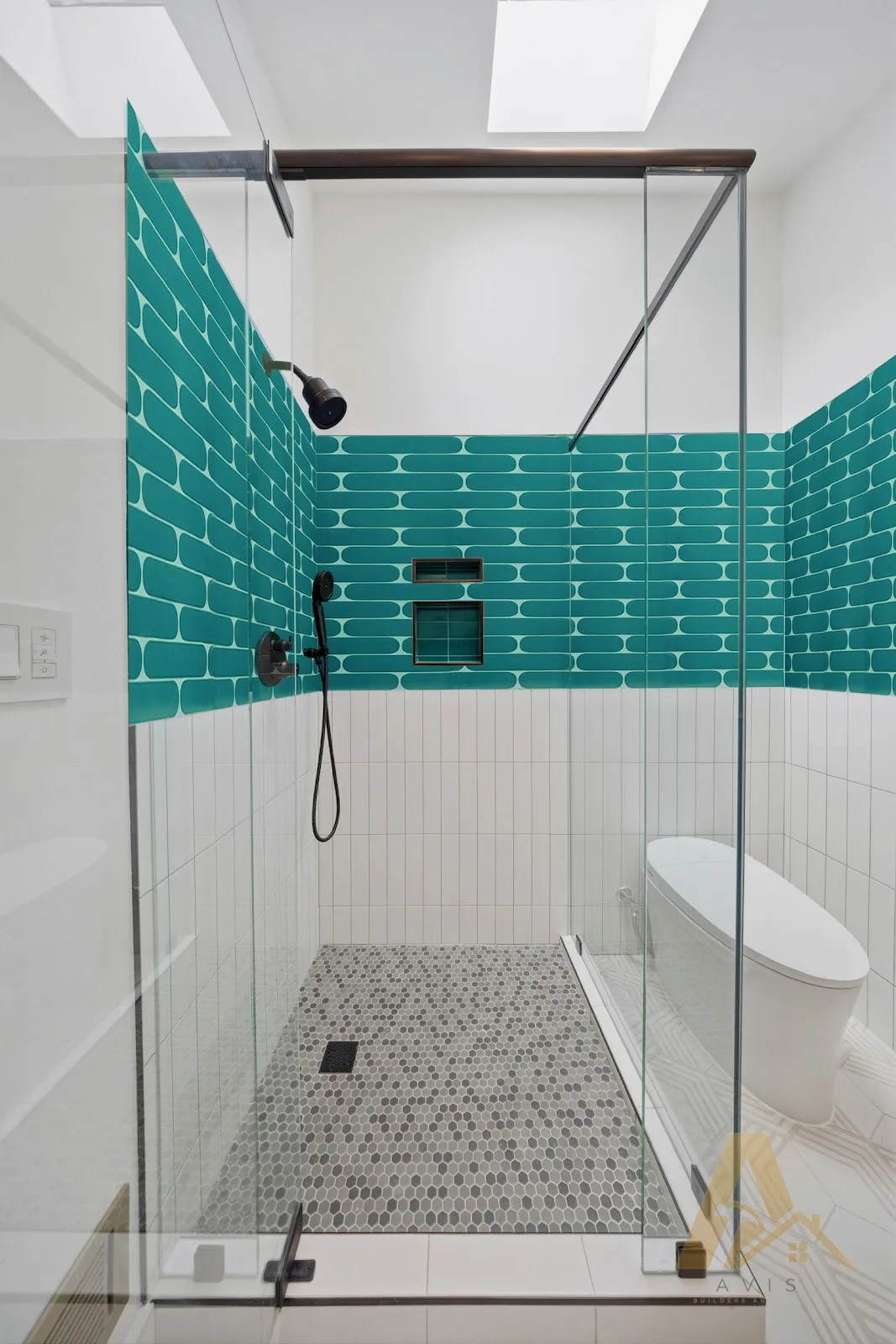 Glass-enclosed shower with teal tile, black shower fittings and a mosaic floor