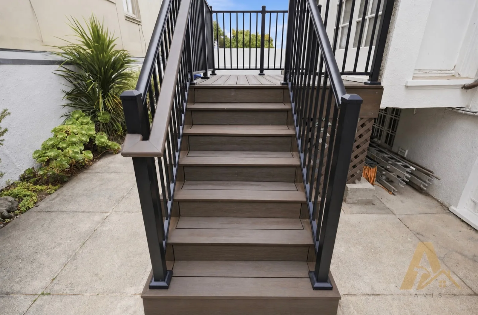 Composite deck stairs with black metal balusters and a wood-tone handrail