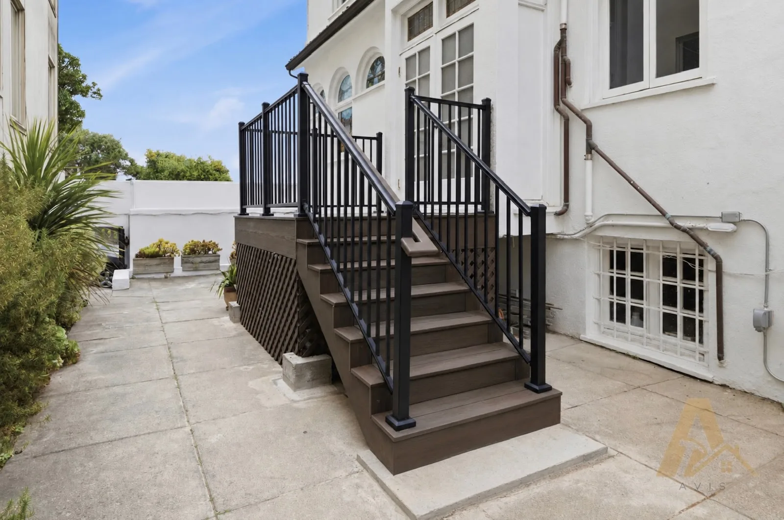 Finished composite stair with black metal railing and a lattice screen under the landing
