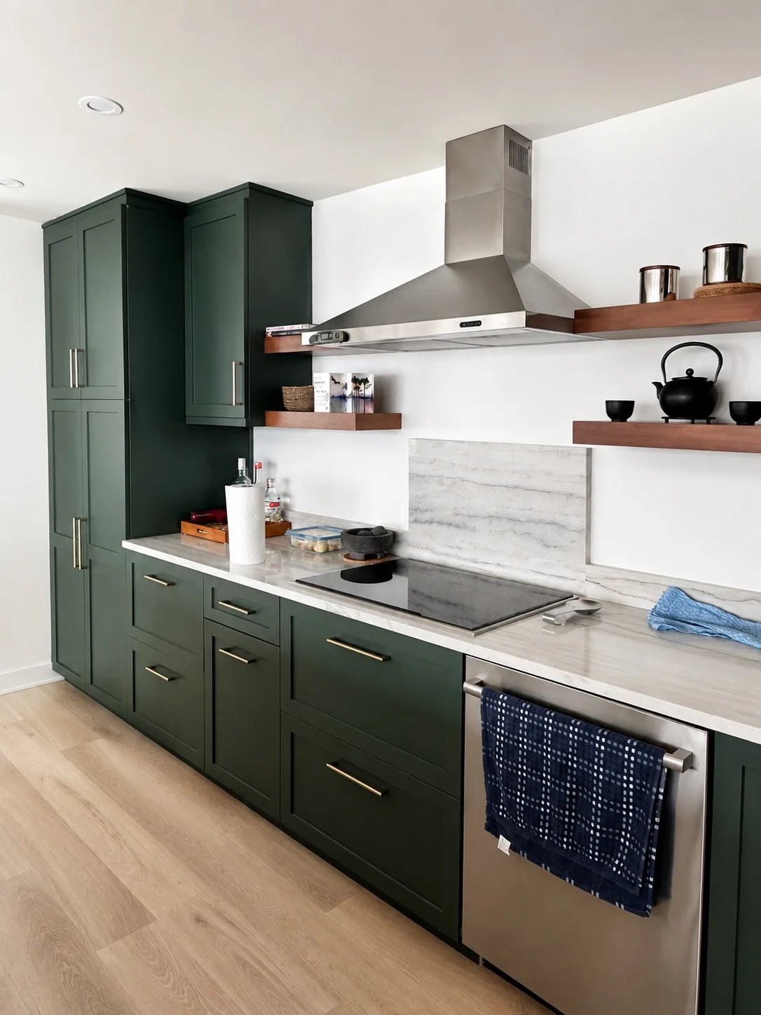 Dark green kitchen with a stainless hood, floating wood shelves and marble backsplash