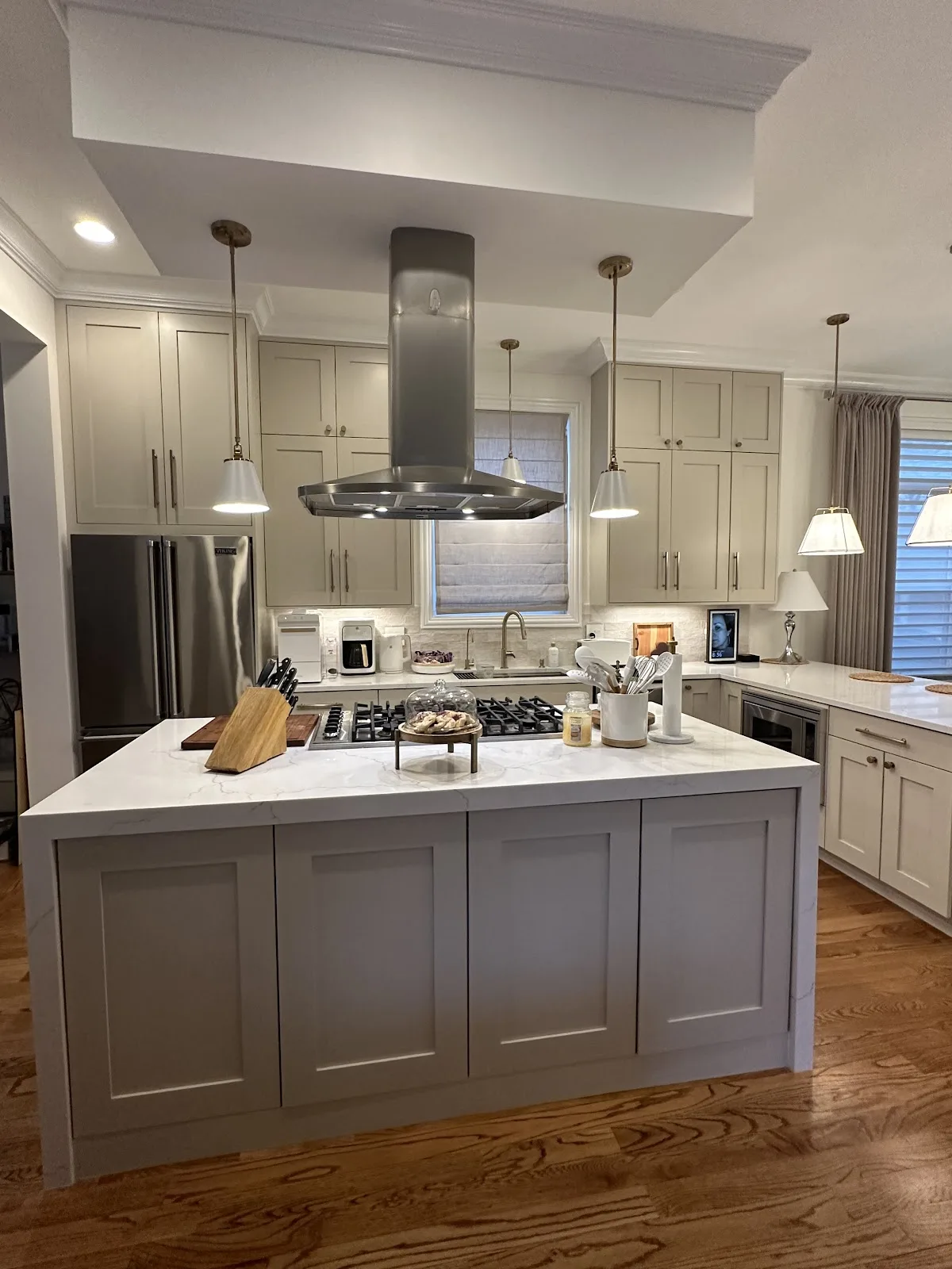 Greige shaker kitchen with a quartz island and stainless island hood
