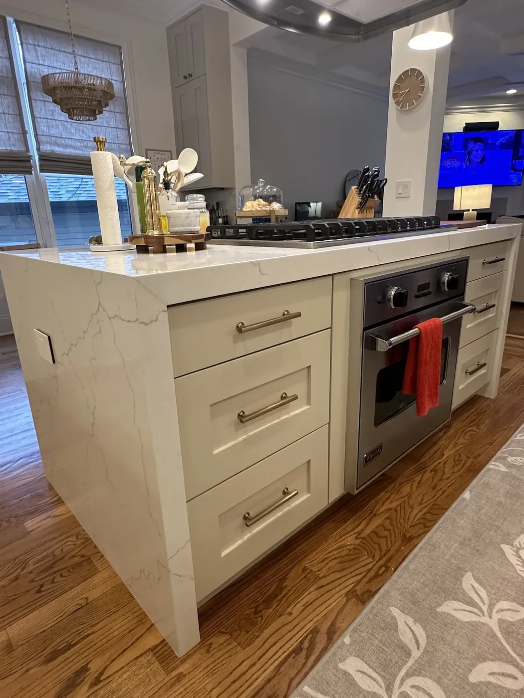 Greige shaker kitchen with a waterfall quartz island and built-in oven