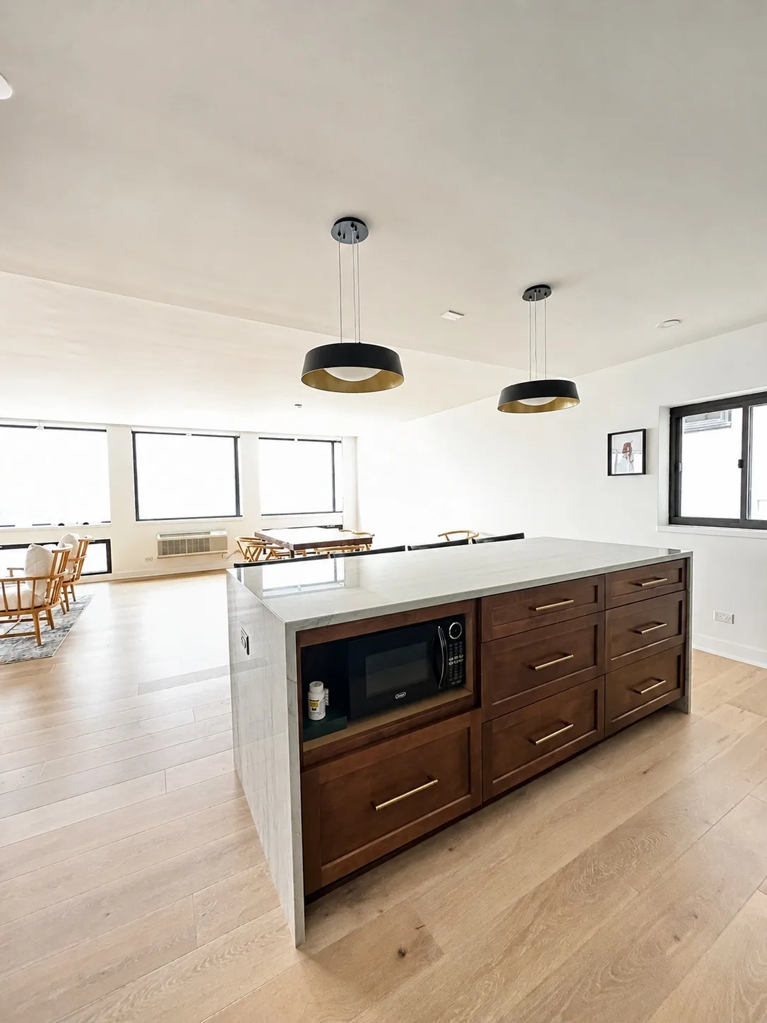 White kitchen with a dark wood island, black pendants and oak flooring