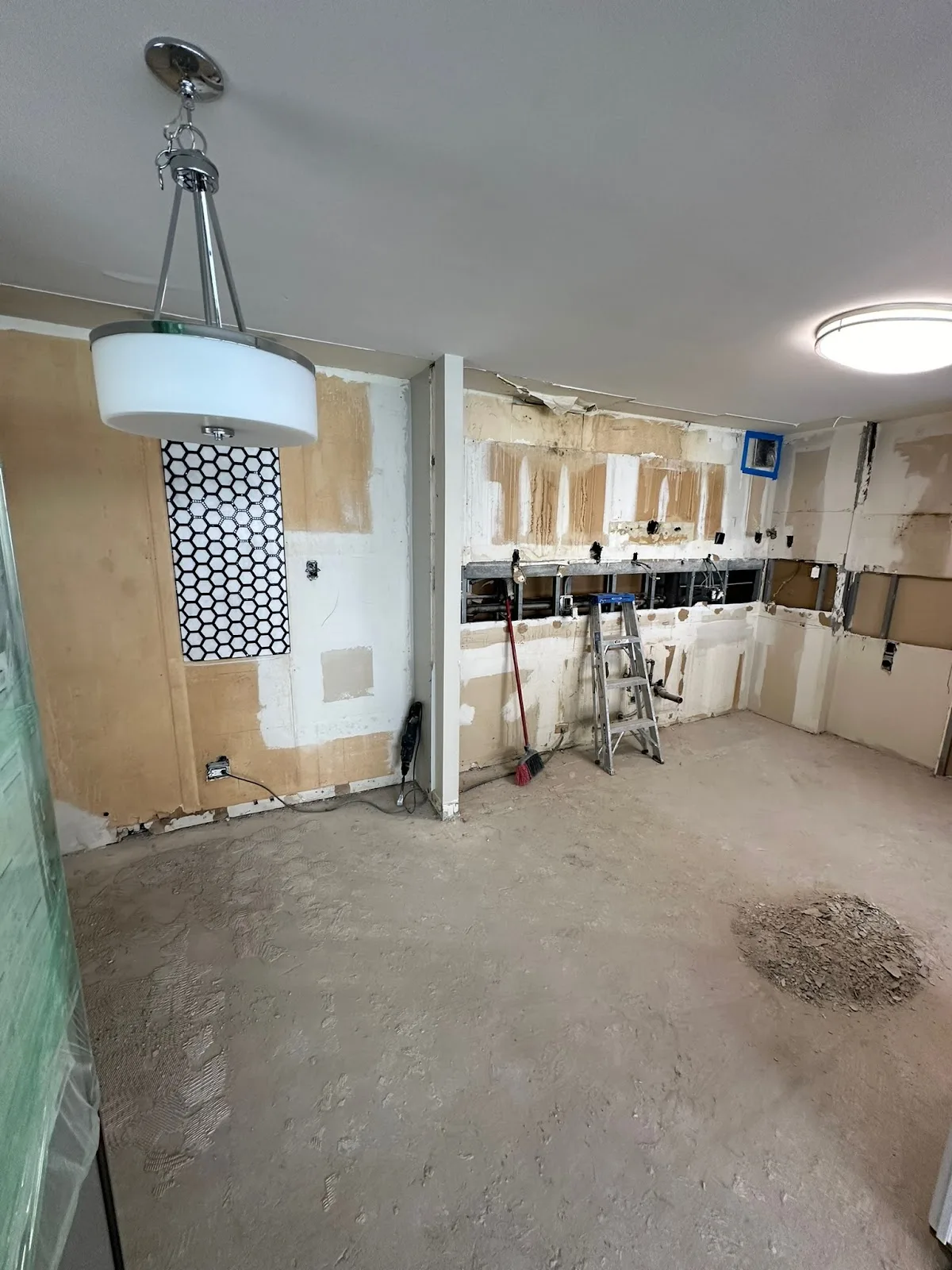 Demolition in progress with exposed studs, a step ladder and debris
